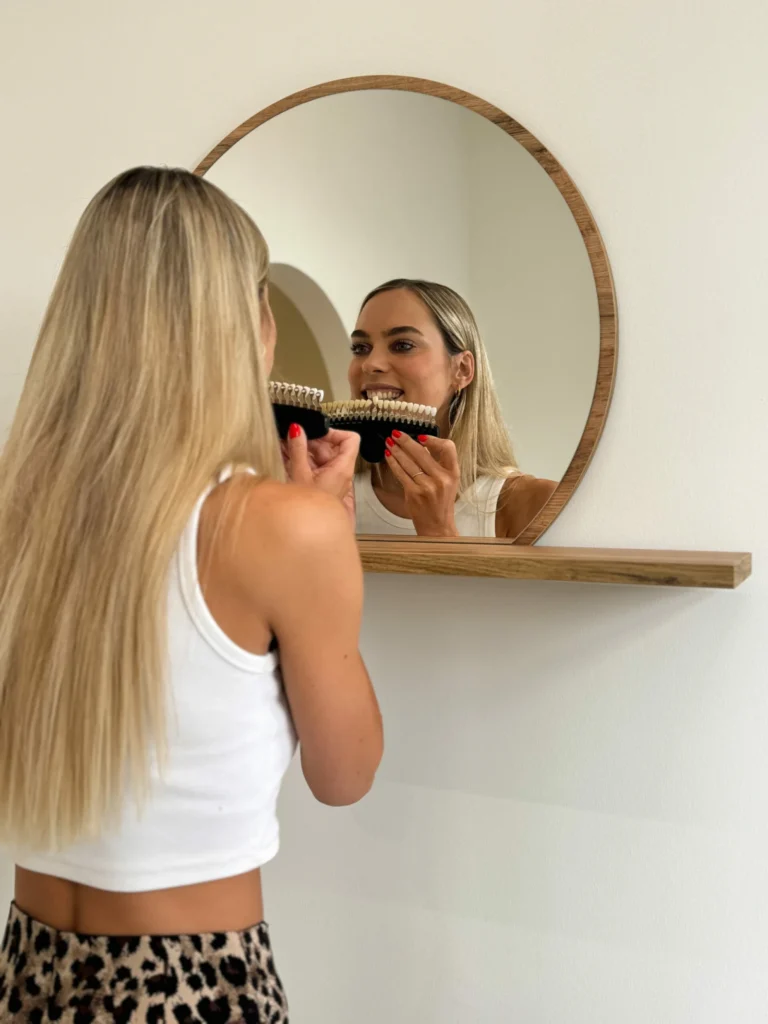 Kundin prüft ihren Zahnfarbton im Spiegel bei MOOI Aesthetics